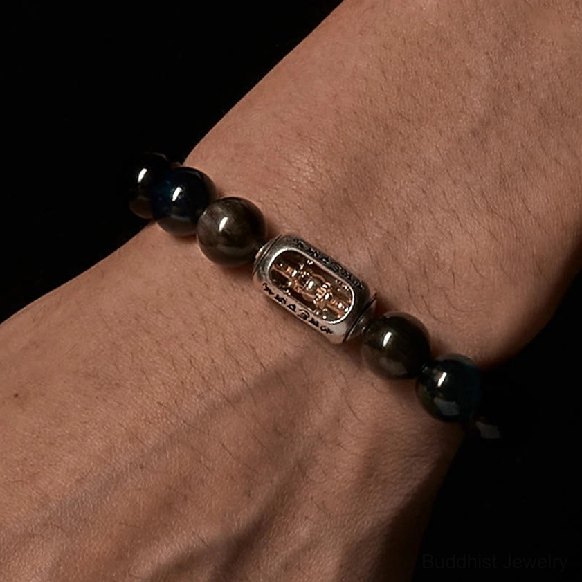 Side close-up detail of Buddhist bracelet on forearm showing dark gemstone beads and engraved metal spacer charm