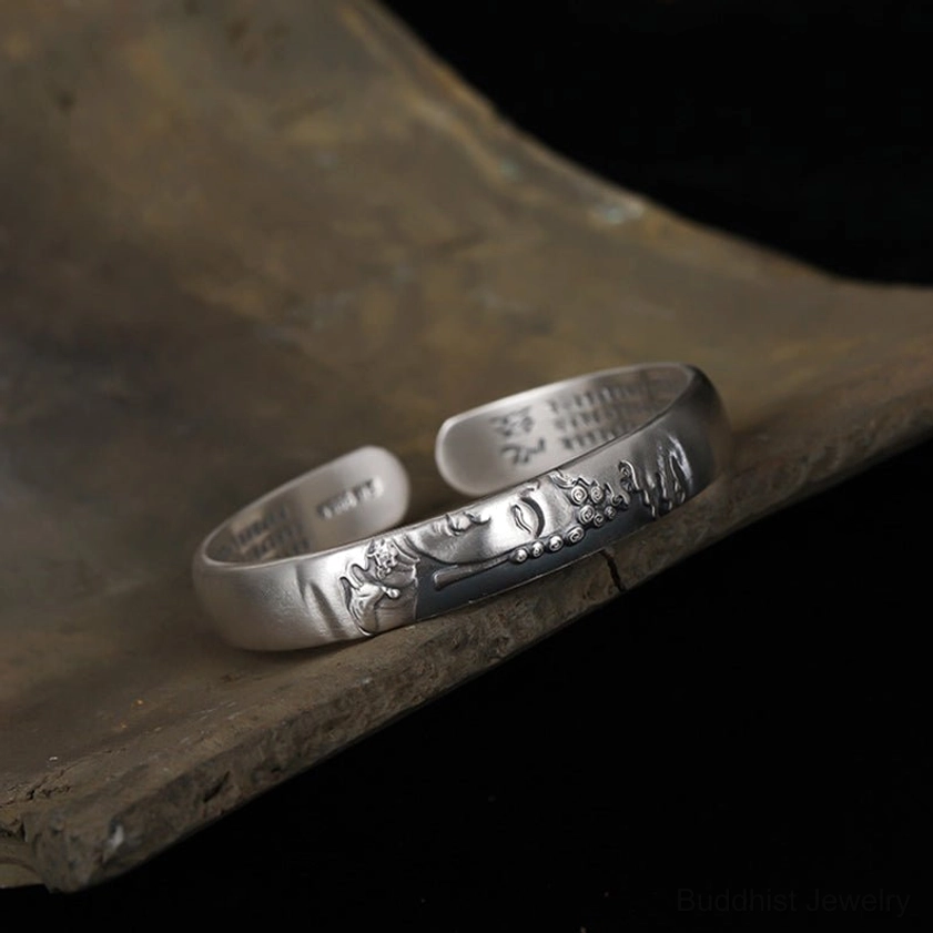 Low-angle side profile of sterling silver Buddha open cuff bracelet, dark silver tone showing embossed Buddha details and inner sutra engravings