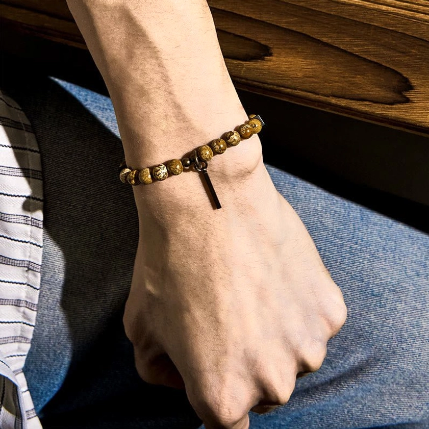 Close-up side view of natural stone beaded Buddhist bracelet with copper clasp and bar pendant