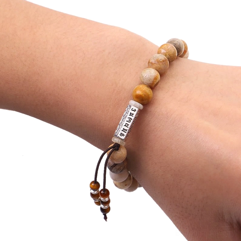 Weathered stone Om Mani Padme Hum bracelet worn on wrist showing comfortable fit and tassel accent