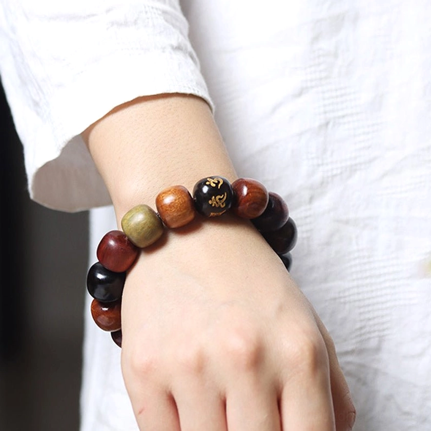 Meditation bracelet worn on human wrist against white clothing background, showing proper fit and mixed natural wood bead colors in daily wear