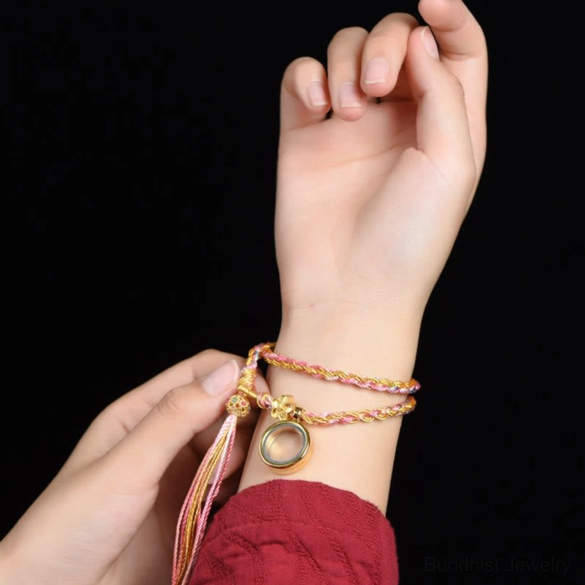 Buddhist lucky braided string bracelet worn on wrist - double wrap design with metal pendant and tassel close-up