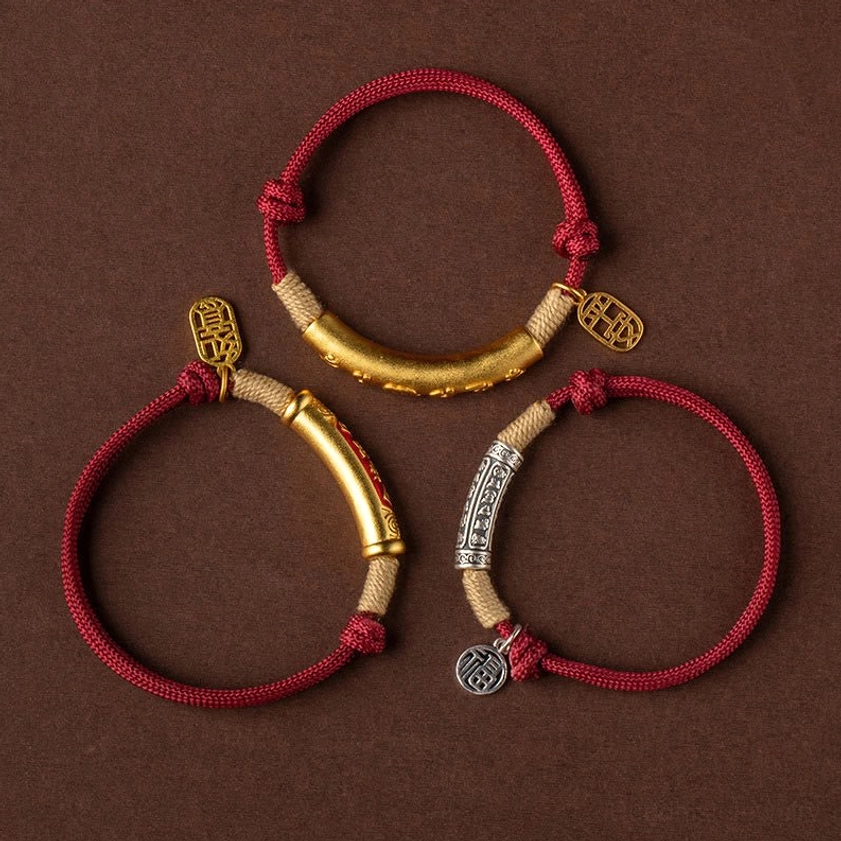 Set of three Buddhist protection bracelets with silver and copper metal charms red cord flat lay