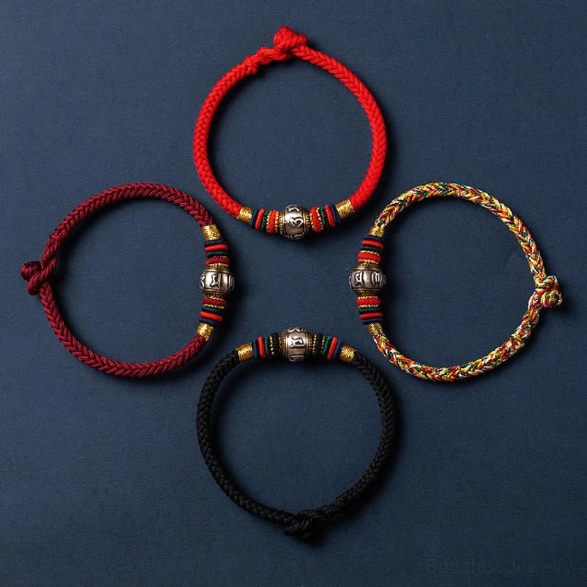 Collection of Buddhist braided string bracelets in multiple colors including red, black, and multicolored options with silver decorative beads