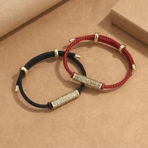 Couple handmade Buddhist braided string bracelets in red and black with gold copper accents on kraft paper