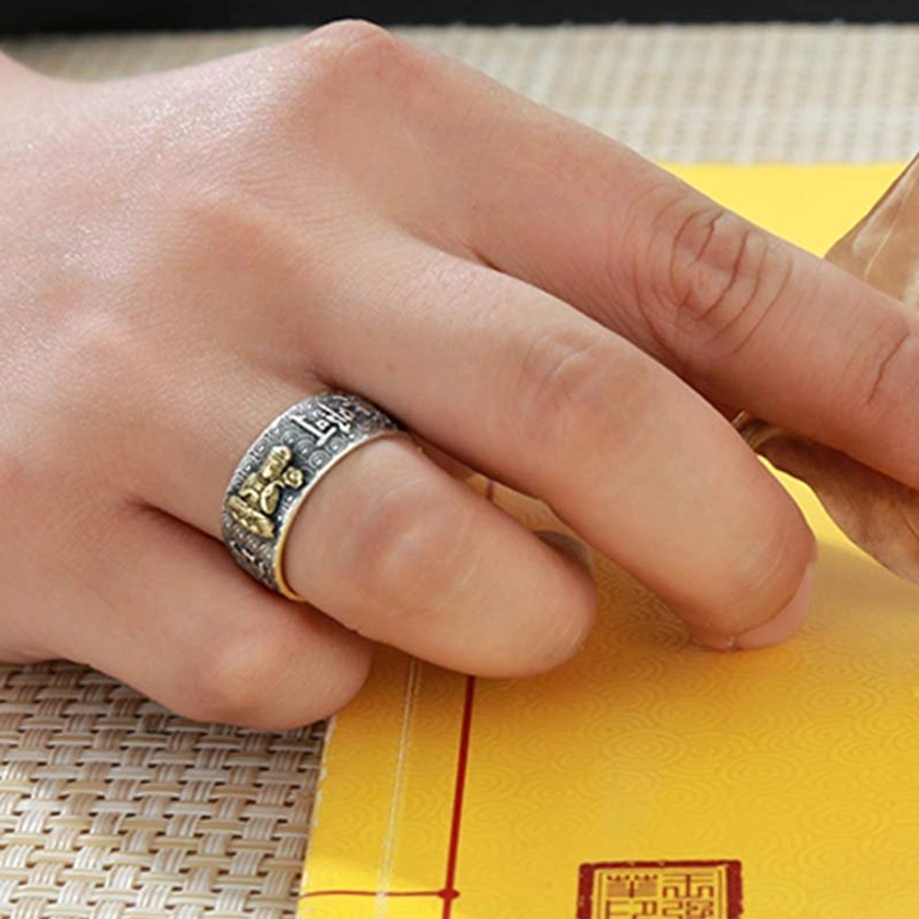 Adjustable Buddhist Buddha ring worn on index finger, mixed silver and gold tone with engraved decorative patterns on woven mat background