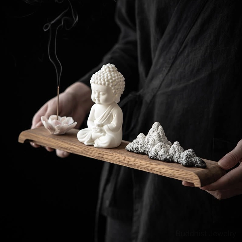 Hand holding portable Buddhist incense burner set with burning incense and rising smoke