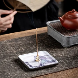 Handcrafted ceramic Buddhist incense burner tray with landscape design displayed on traditional tea table with brass holder