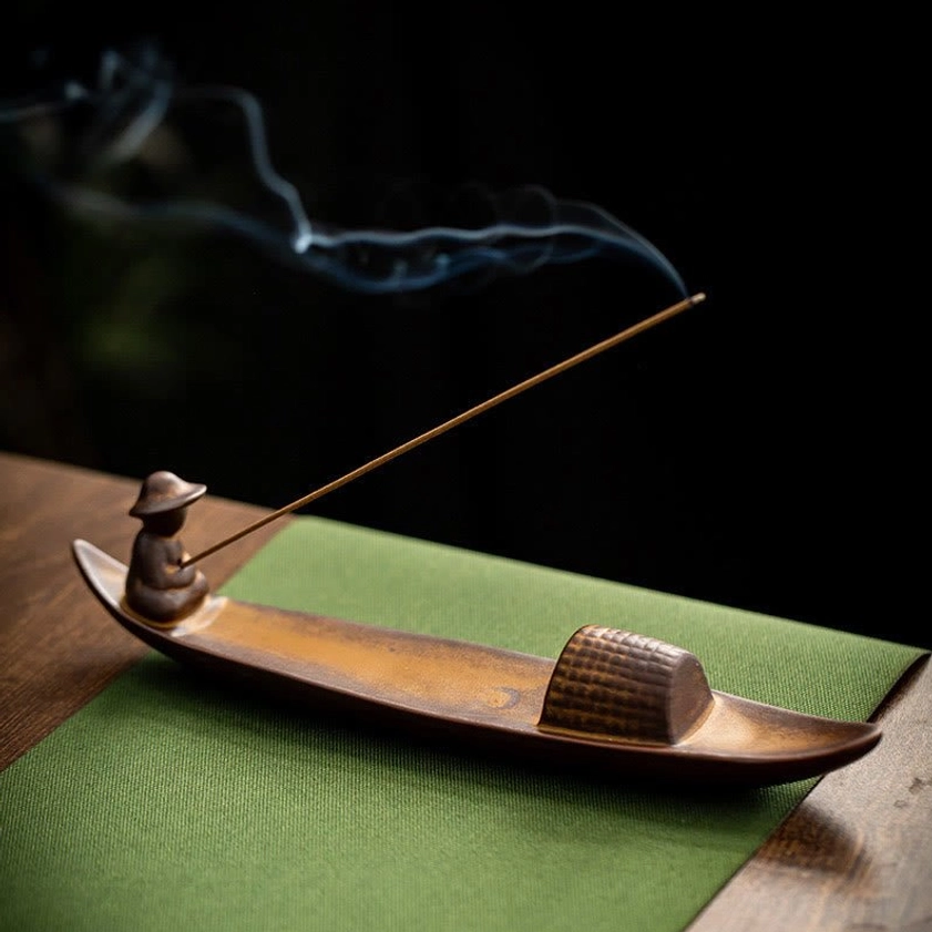 Meditation incense burner on green linen showing two-tone brown ceramic with drifting incense smoke