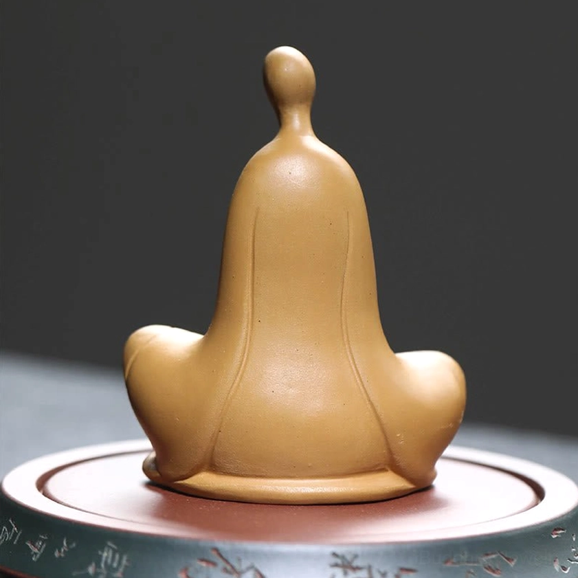 Yellow Buddhist ceramic statue back view - rear silhouette on engraved circular base