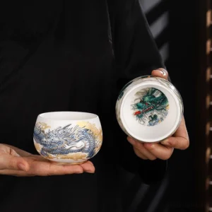 Blue dragon gilt ceramic gongfu tea cup held in hands displaying detailed hand-painted Buddhist artwork
