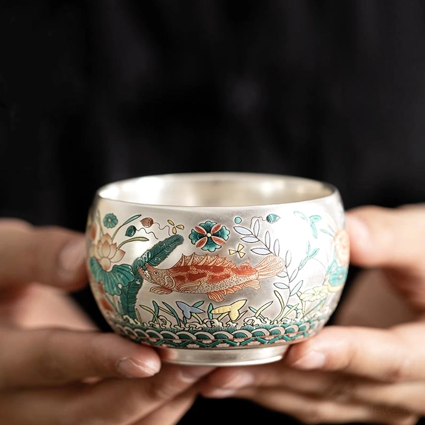 Handcrafted Buddhist enameled ceramic kung fu tea cup with auspicious fish and lotus aquatic design, silver interior close-up view