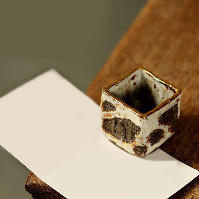 Artistic display of hand-painted Buddhist ceramic teacup on wooden table showing embossed side patterns with white crackle glaze finish