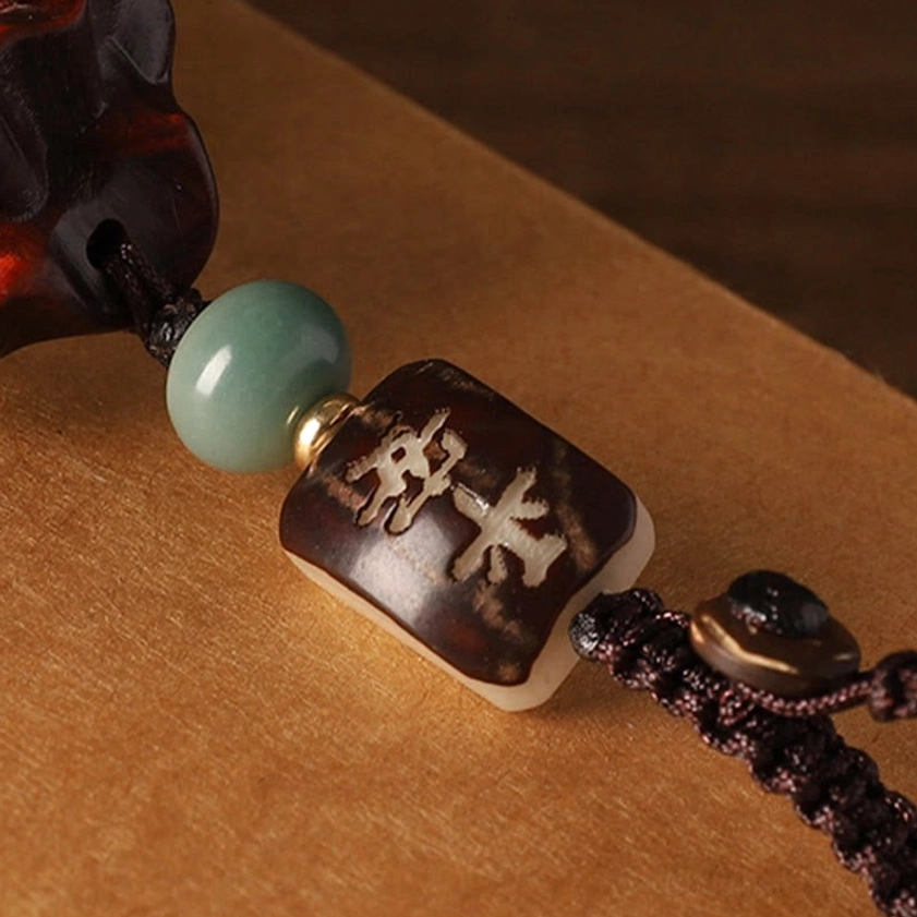Buddhist charm accessory components including carved ping an peace bead, green jade bead, braided cord, and metal accent beads