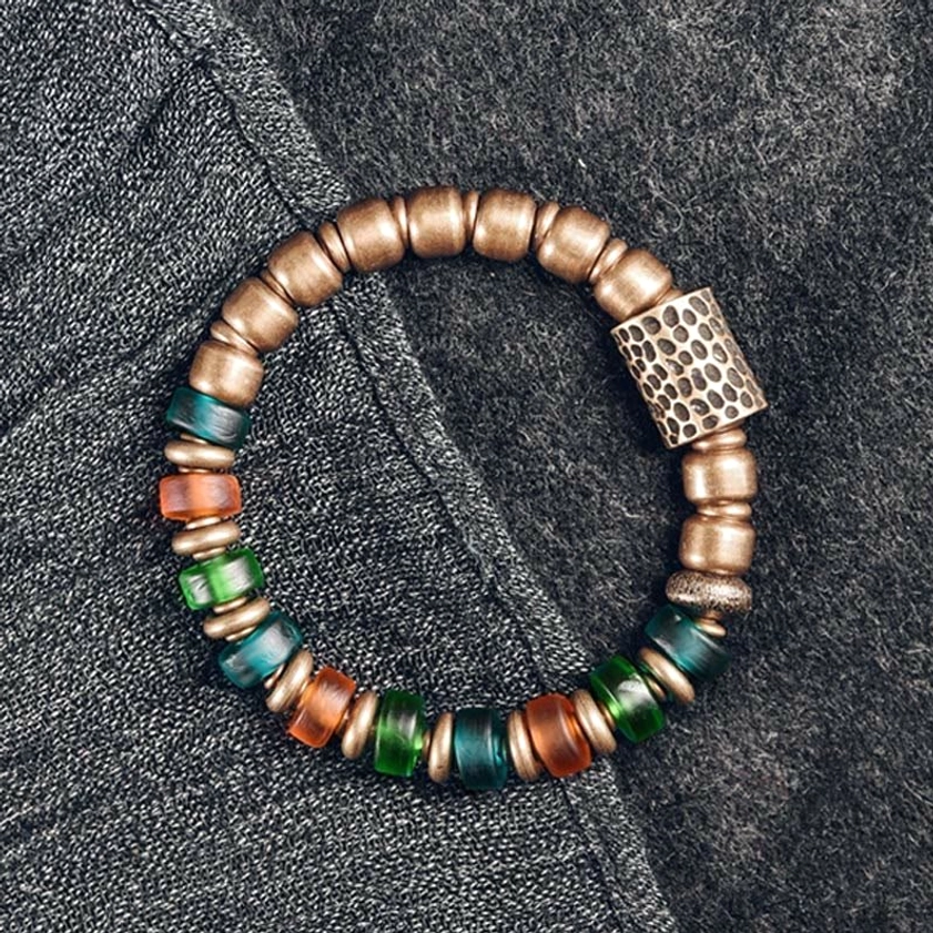Buddhist colorful glass bead copper bracelet flat lay denim background with hammered metal accent and mixed bead tones
