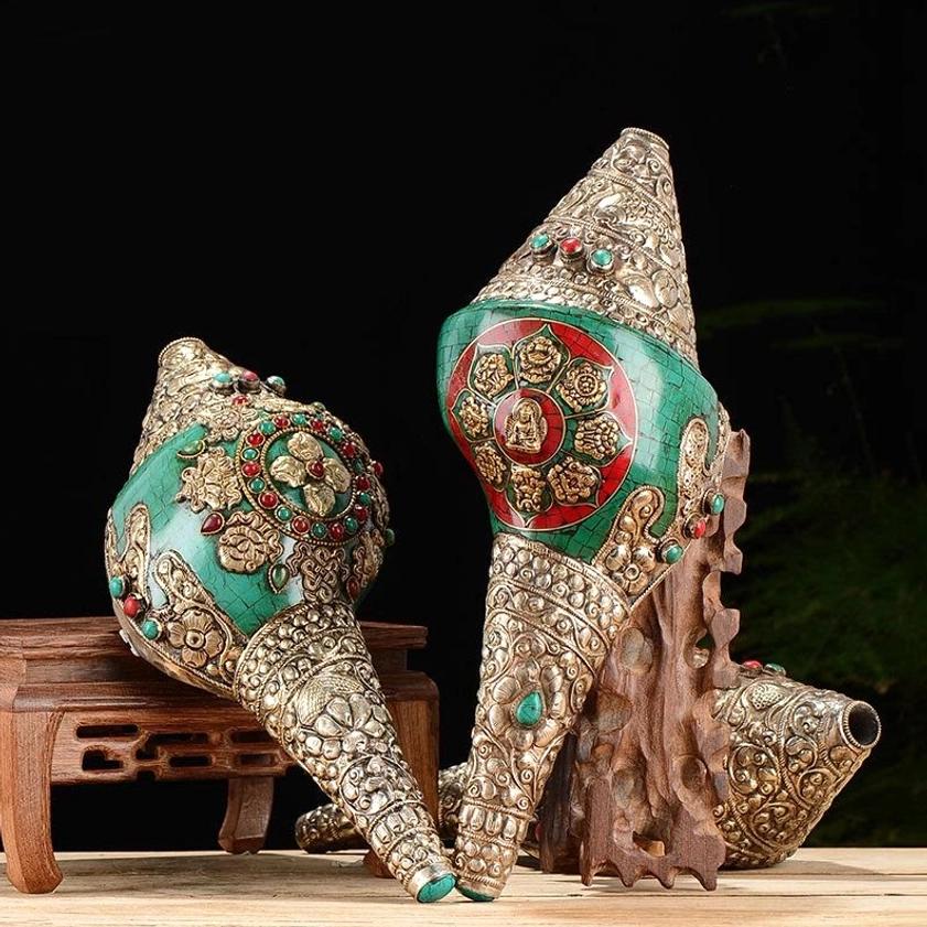 Two Tibetan Buddhist conch shell ornaments side by side on wooden root carving stand, featuring mandala Buddha patterns and elaborate silver craftsmanship