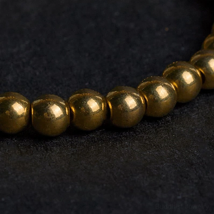 Side macro view of uniform round golden copper beads showing metallic finish and craftsmanship