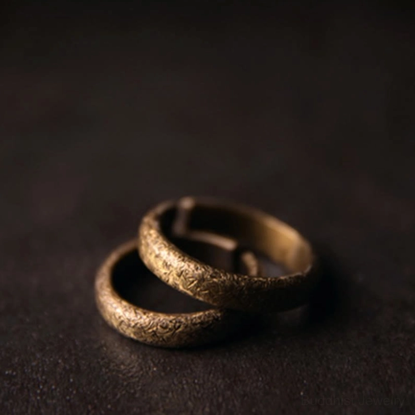 Pair of vintage copper Buddhist rings with textured bronze finish, stacked overhead view for couples