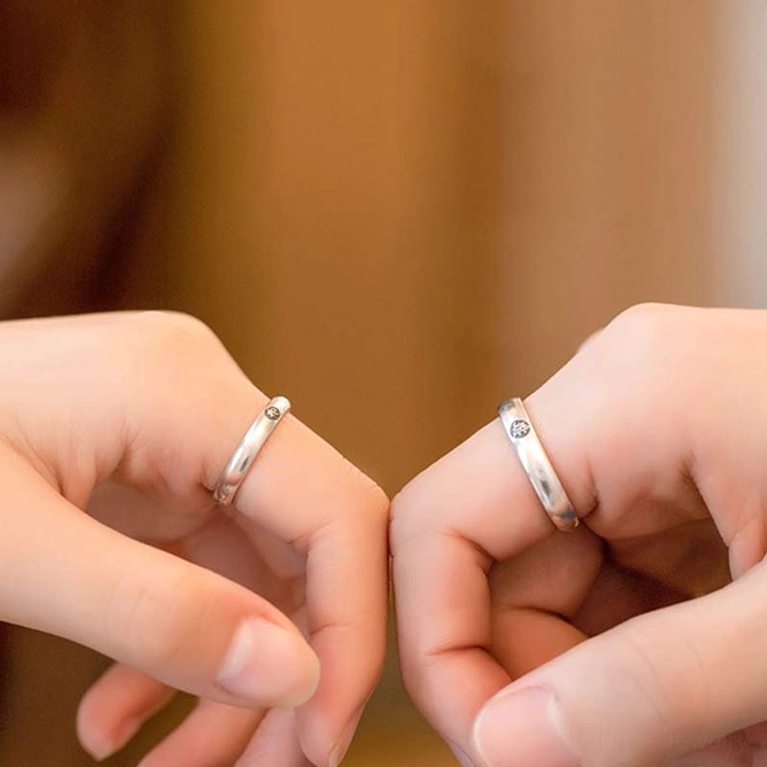 Matching 925 sterling silver Buddhist couple rings held together, showing synchronized zodiac designs