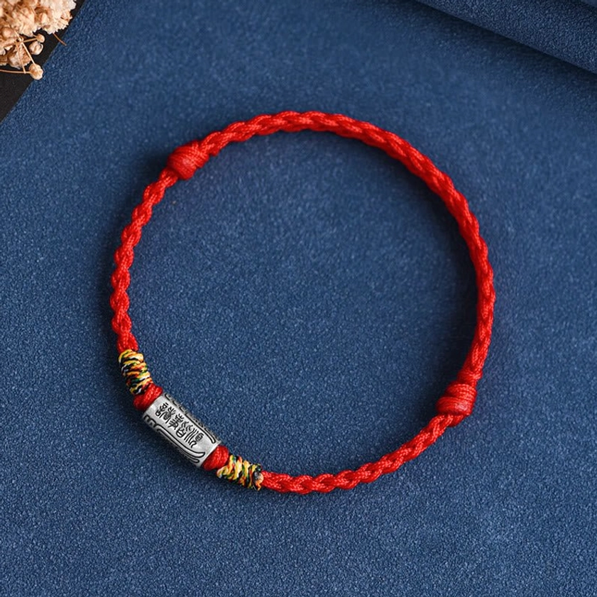 Buddhist blessing bracelet with dark red burgundy rope and engraved sterling silver charm, deep red protection symbolism display