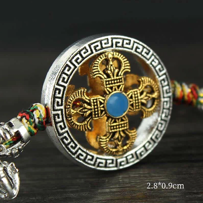 Close-up of gold cross Vajra center with silver dharma wheel frame and blue stone inlay detail