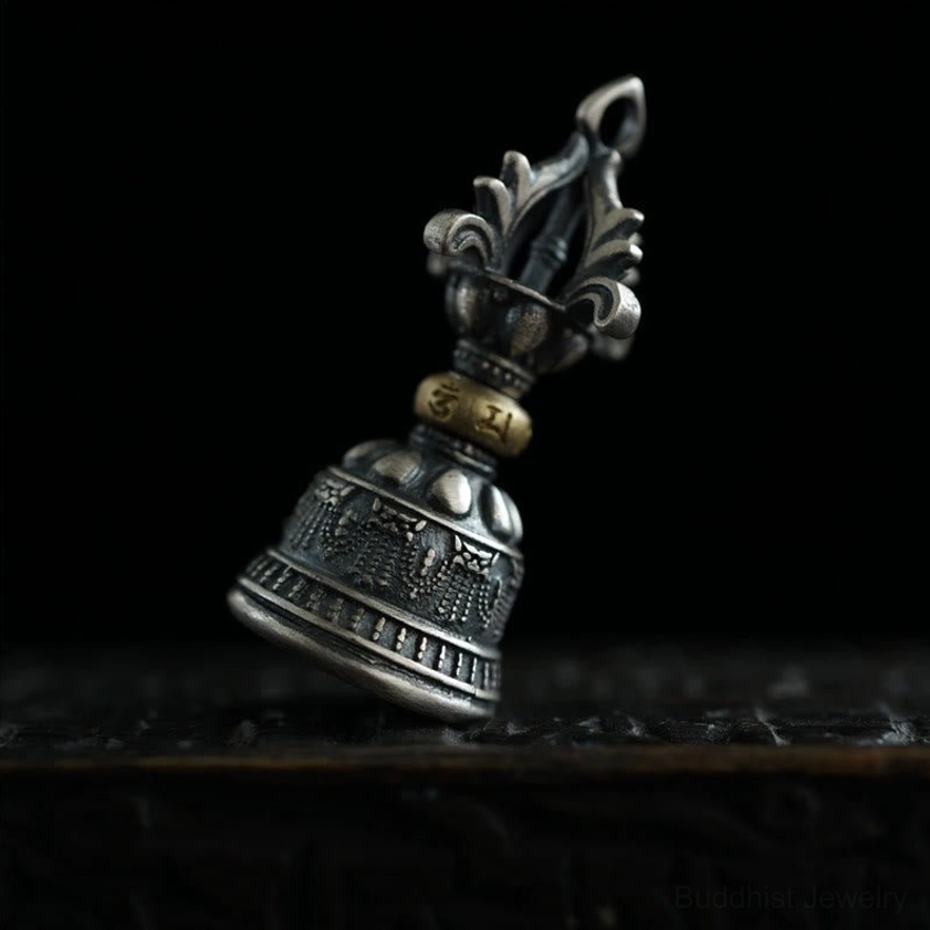 Low angle side view of sterling silver vajra pendant showing brass spacer ring and intricate engraved relief details