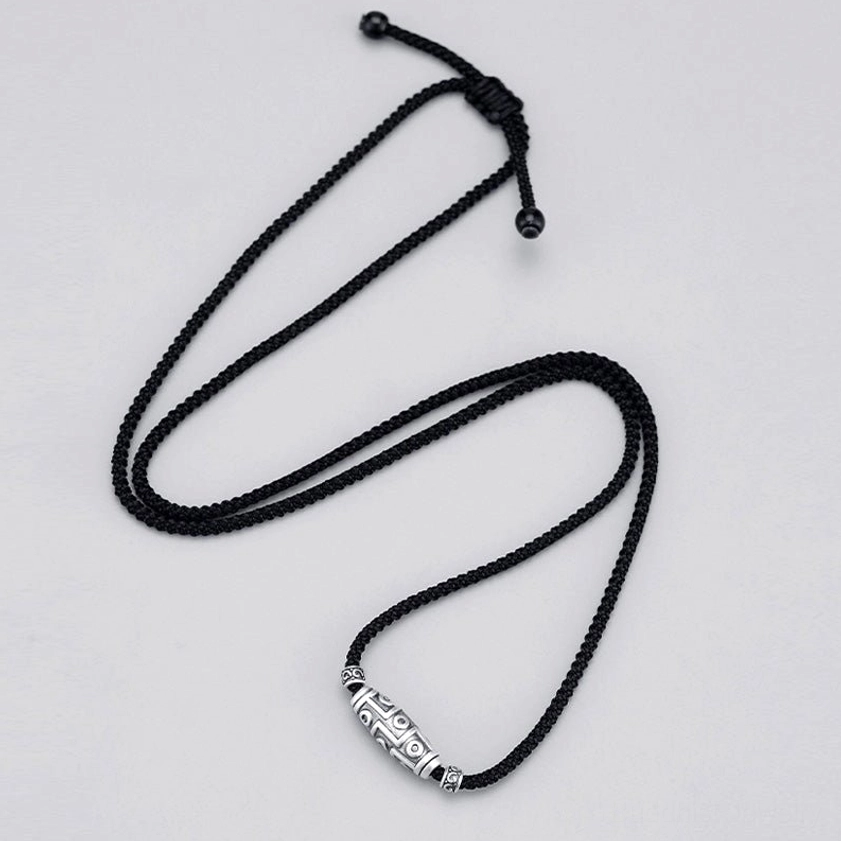 Nine-eye dzi pendant necklace flat lay on black background showing loose pull cord adjustable design