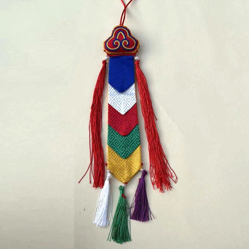 Buddhist embroidered tassel wall hanging on light background with red silk tassels