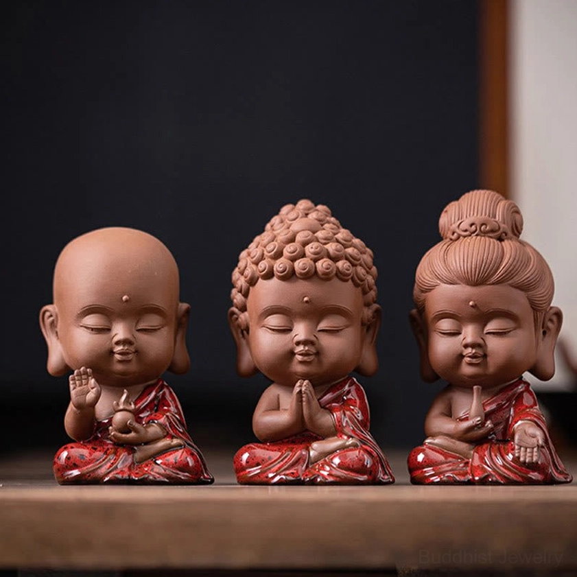 Buddhist ceramic figurines arranged on meditation altar desktop shrine with three sacred beings for spiritual contemplation and mindfulness practice