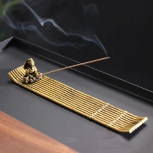 Buddhist fisherman bamboo raft incense burner with burning incense and antique bronze finish, top-down view showing smoke and traditional craftsmanship