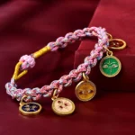 Handmade five gods of wealth Buddhist braided rope bracelet with multicolored woven string and enamel metal charms on burgundy velvet background