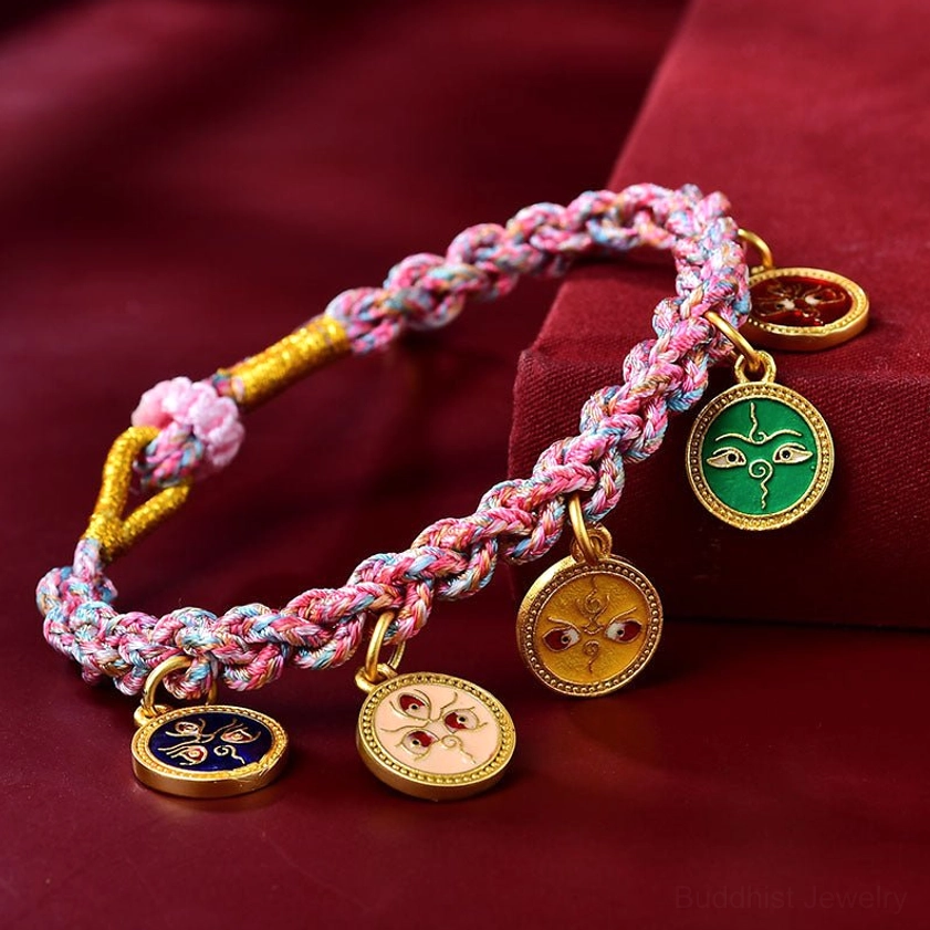 Handmade five gods of wealth Buddhist braided rope bracelet with multicolored woven string and enamel metal charms on burgundy velvet background