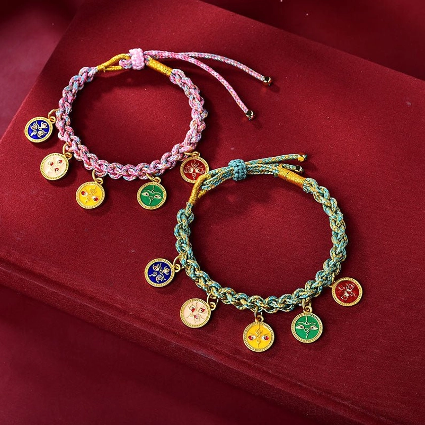 Two styles of Buddhist prosperity bracelets with different colored woven ropes and multiple enamel fortune charms displayed on burgundy velvet