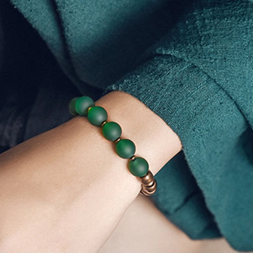 Buddhist gemstone bracelet featuring green agate beads with bronze spacers worn on wrist