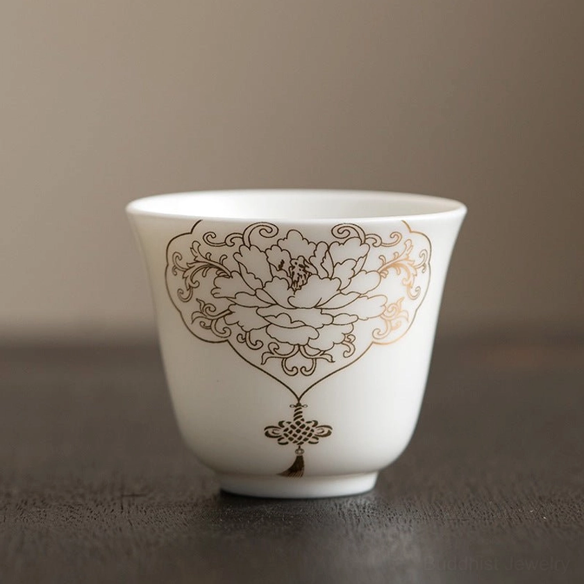 Small Buddhist ceramic kung fu tea cup with hand-painted golden peony design, traditional Eastern craftsmanship