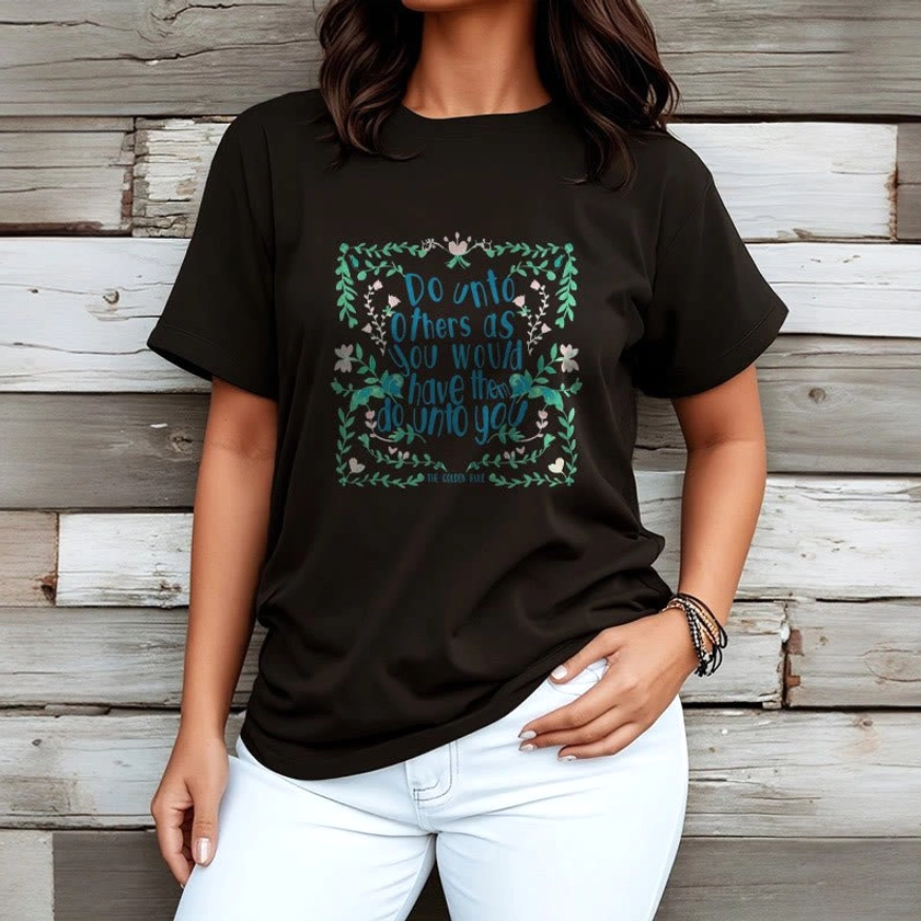Woman wearing black Buddhist compassion graphic tee with golden rule floral print wooden wall backdrop