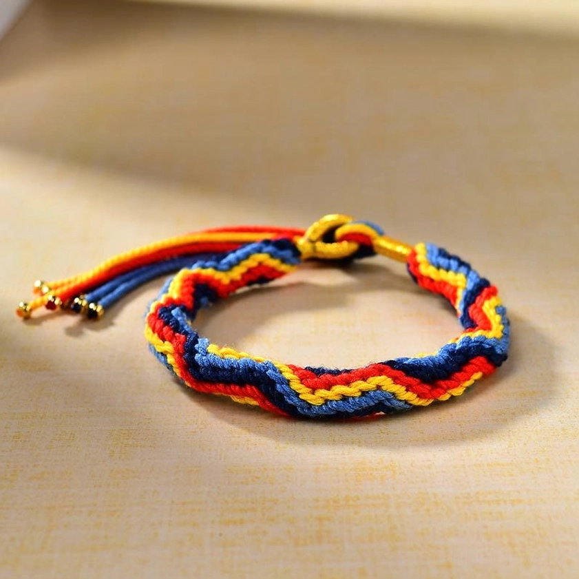 Three-quarter side view of twisted woven Buddhist string bracelet with gold fastener and beaded tassel ends showcasing artisan handcraft details