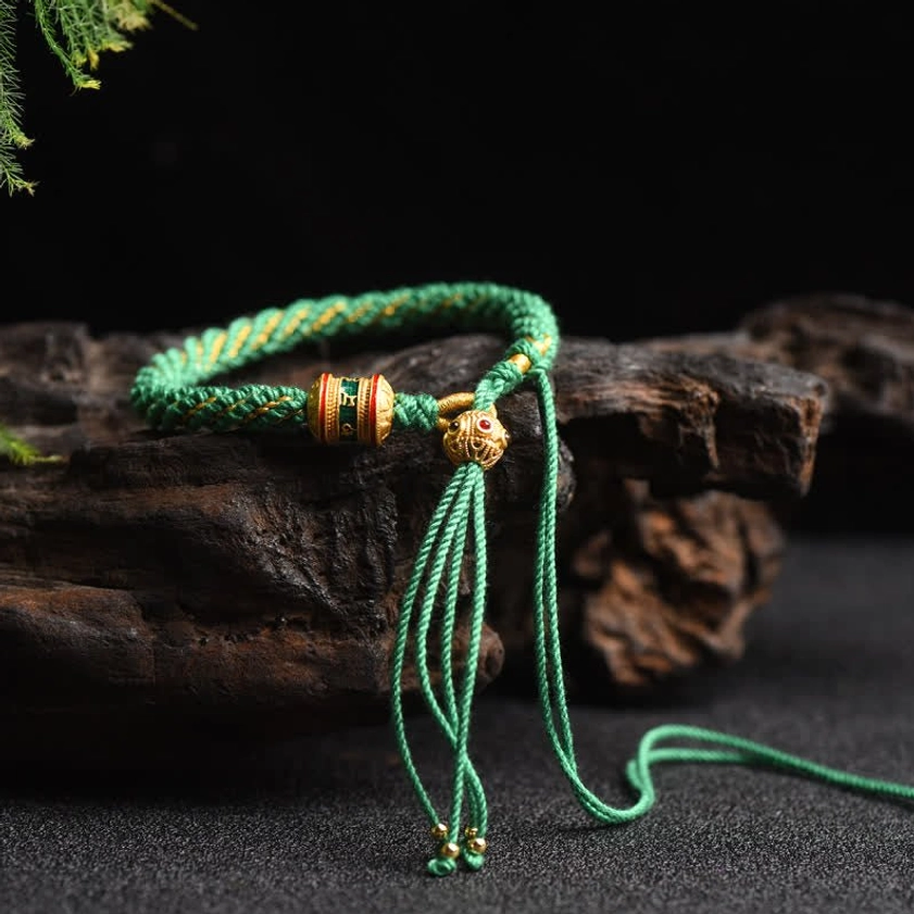 Green Buddhist lucky charm string bracelet with prayer wheel bead and handcrafted woven cord details