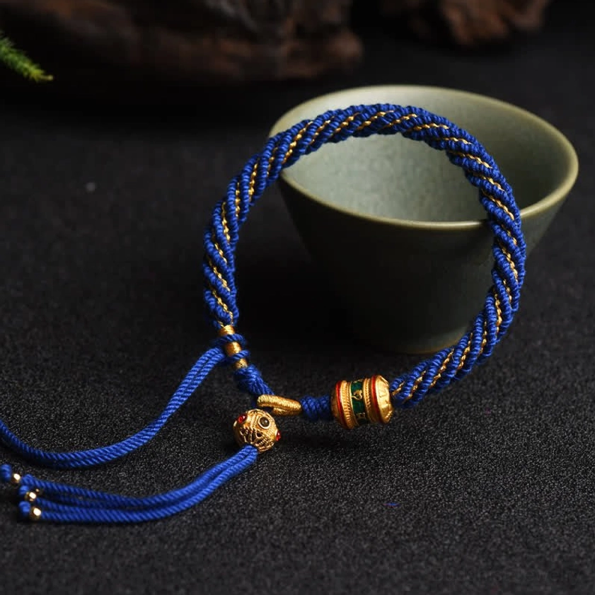 Buddhist string bracelet prayer wheel charm in green color with handwoven braided cord and beaded tassel