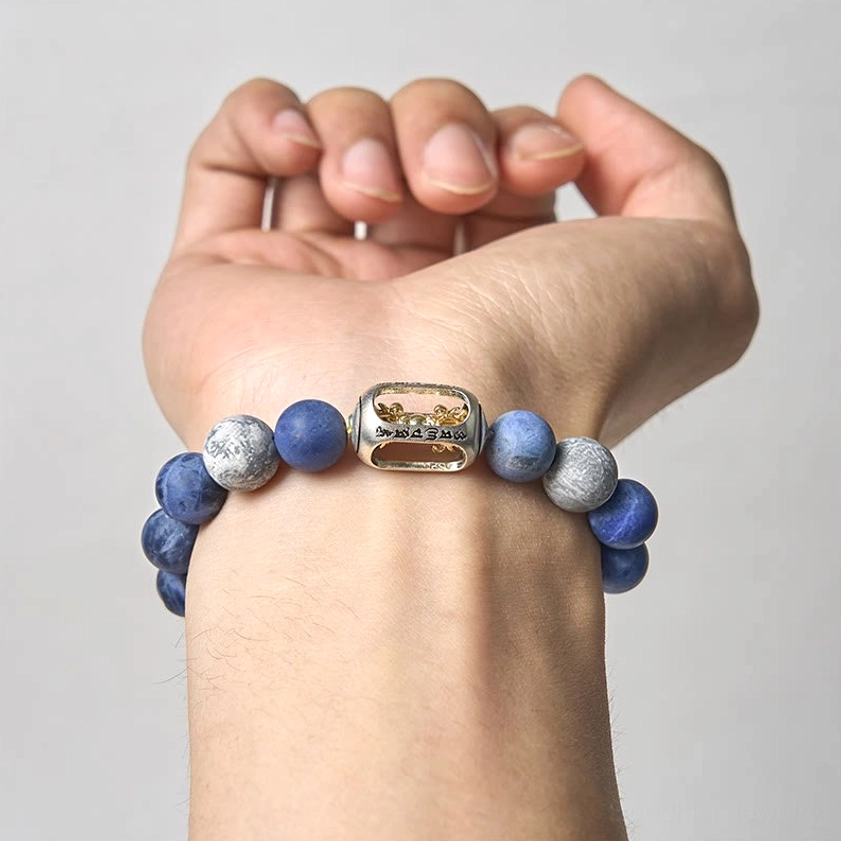 Hand wearing natural stone Buddhist bracelet with engraved metal mantra spacer bead close-up