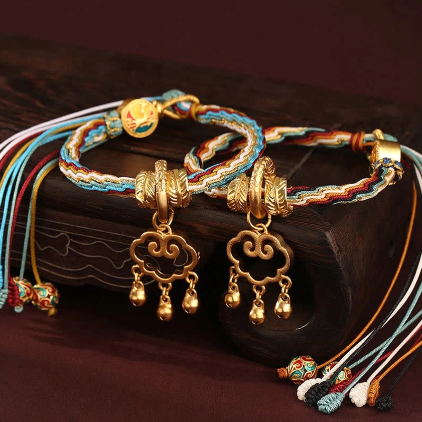 Handmade Buddhist healing bracelet detail showing intricate braiding pattern, ornate gold cloud lock pendant with protective bells and decorative knots