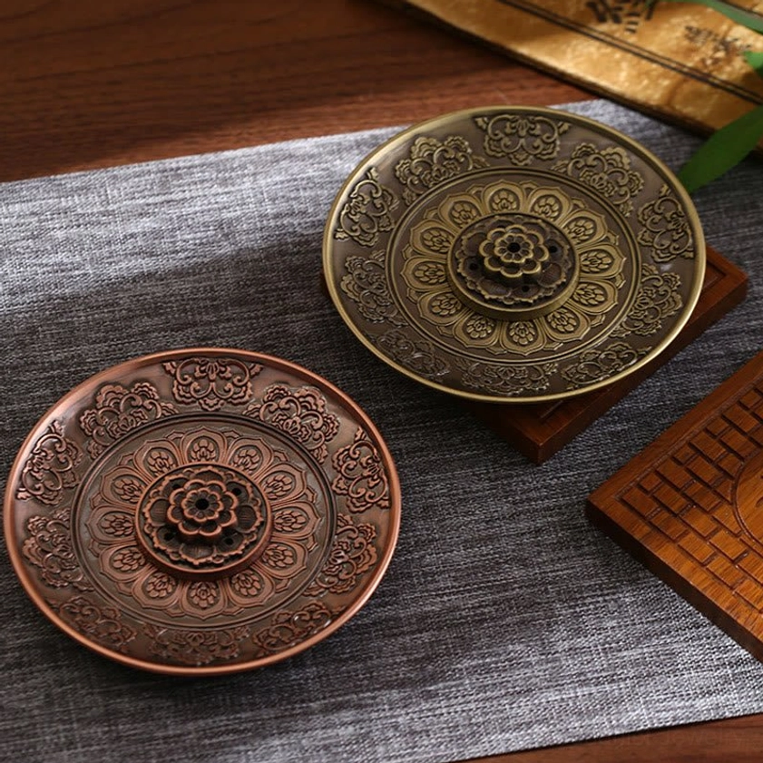 Two Buddhist incense burners in bronze and red copper finish displayed in study setting, overhead tabletop view