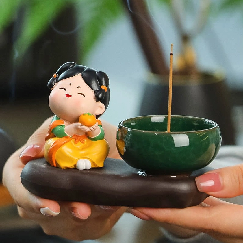 Buddhist ceramic incense burner with graceful lady figurine and orange motif held in hand, showing green glazed bowl and brown ceramic base