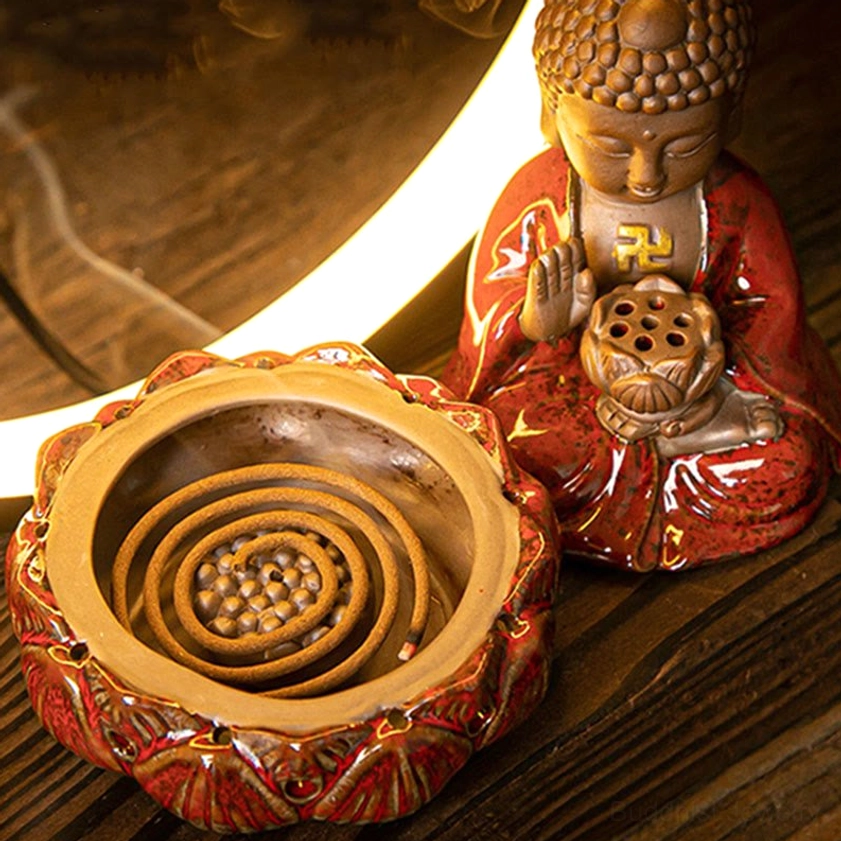 Top-down view of lotus-shaped incense tray with coiled incense stick and red glazed Buddhist figure