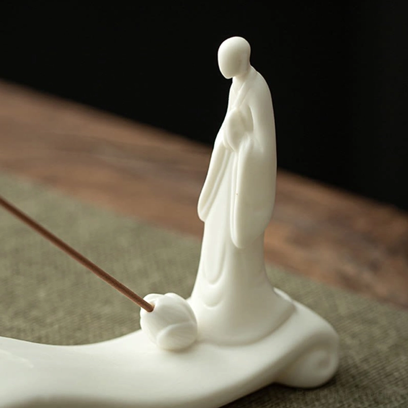Handmade ceramic Buddhist incense holder side view showing seated monk and waves detail