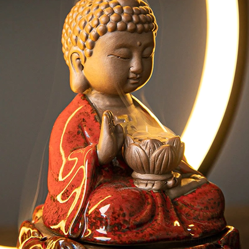 Side view of red ceramic Buddha incense burner with smoke flowing from lotus vessel and backlight ring