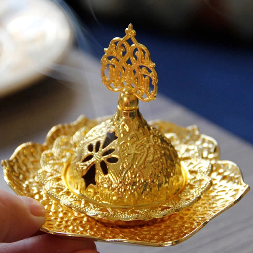 Smoking gold incense burner with detailed hollow carvings and visible fragrant incense smoke