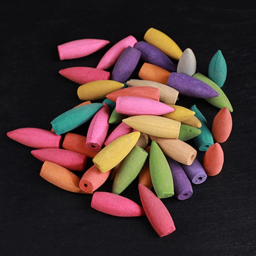 Vibrant mixed Buddhist backflow incense cones loosely scattered on black matte background, showing variety of floral and sandalwood scents available