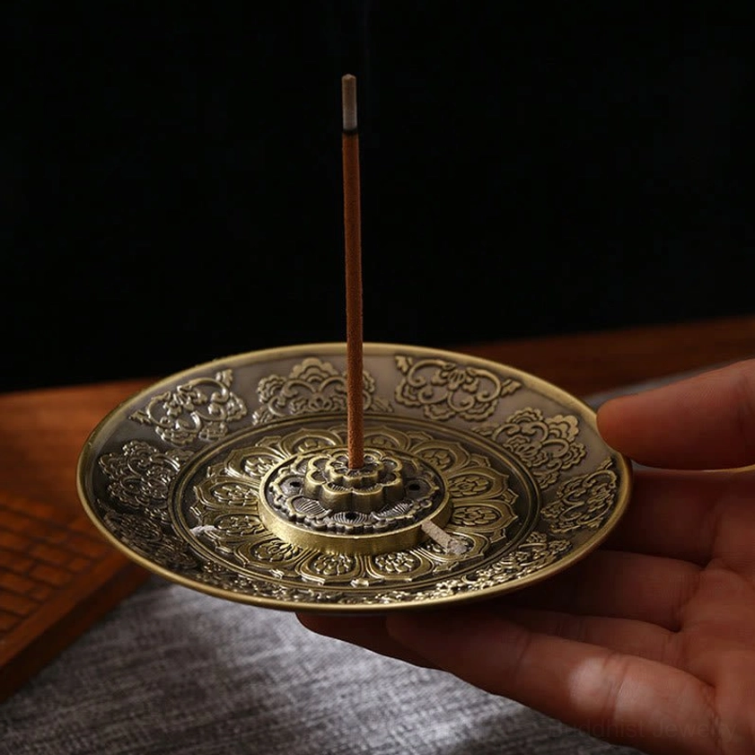 Buddhist incense holder with carved intricate details in bronze tone, three-quarter hand-held view