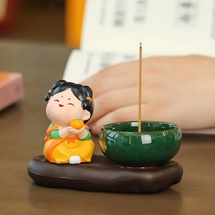 Tang Dynasty-inspired ceramic incense burner with lady figurine in yellow traditional outfit, incense stick burning on wooden desk workspace